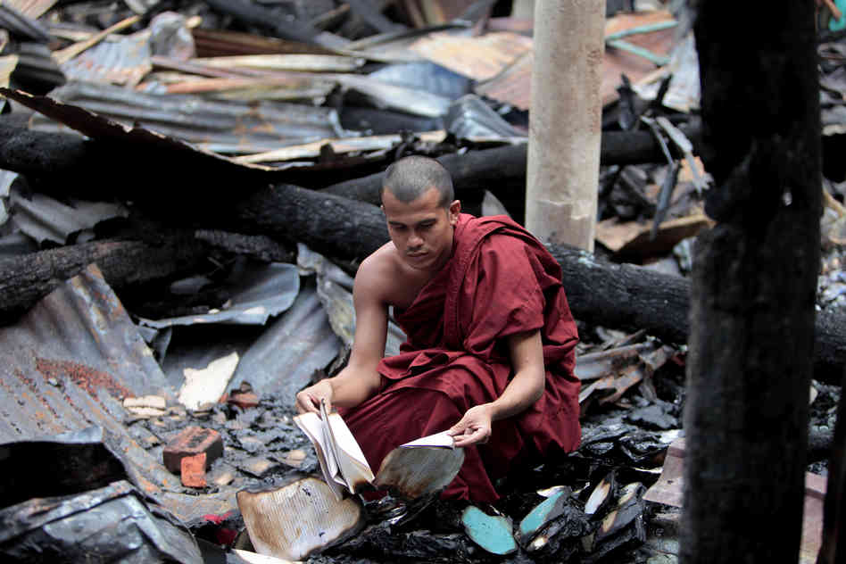 Một nhà sư bên đống kinh sách bị đốt cháy.jpg